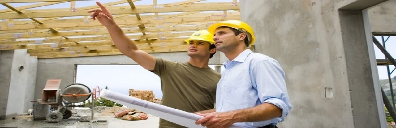 Supervisión de obra con dos hombres con casco y planos